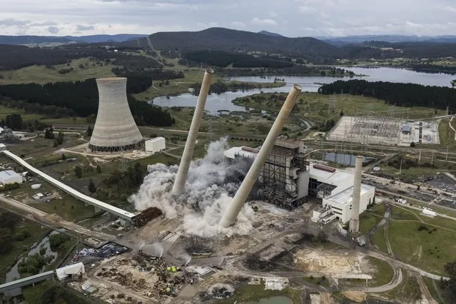 In this aerial view a controlled blast demolishes part of the old Wallerawang Powerstation on November 24, 2021 in Lithgow, Australia. Two large chimney stacks at Wallerawang Power Station were demolished by controlled blast this morning. The demolition is part of plans by to rejuvenate the decommissioned power station into a multi-use area. The Wallerawang Power Station was closed in 2014, with the site acquired by Greenspot in 2020, which plans to develop a large grid-scale battery on the old power station site. (Photo by Brook Mitchell/Getty Images)