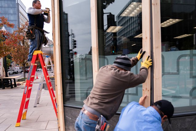 Workers cover the windows of a pharmacy near the White House with plywood ahead of the presidential election in Washington on November 4, 2024. (Photo by Nathan Howard/Reuters)