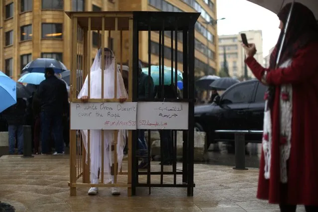 An activist from the Lebanese NGO Abaad (Dimensions), a resource centre for gender equality, dressed as a bride and wearing bandages stands in a golden cage during a protest near the parliament in downtown Beirut on March 15, 2017, as MPs are debating a vote against article 522 in the Lebanese penal code. The article shields rapists from prosecution on the condition that they marry their victim, a phenomenon that is still practised in the country, especially among conservative families whose chief aim is to preserve the family's so-called “honour”. (Photo by Patrick Baz/AFP Photo)