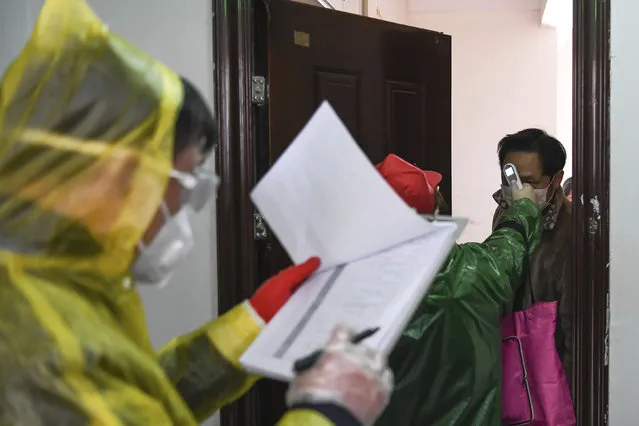 In this February 18, 2020, photo released by Xinhua News Agency, workers go door to door to check the temperature of residents during a health screening campaign in the Qingheju Community, Qingshan District of Wuhan in central China's Hubei Province. Protective suit-clad inspectors in the epicenter of China's viral outbreak went door-to-door to find every infected person in the central city suffering most from an epidemic that is showing signs of waning as new cases fell for a second day. (Photo by Cheng Min/Xinhua via AP Photo)