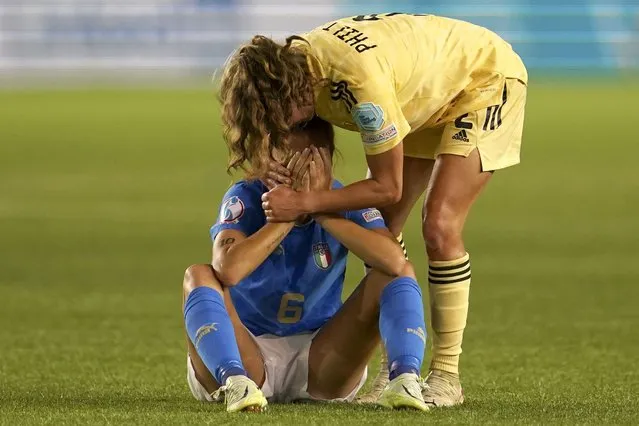 Belgium's Davina Philtjens comforts Italy's Manuela Giugliano sitting on the ground at the end of the Women Euro 2022 group D soccer match between Italy and Belgium at the Manchester City Academy Stadium, in Manchester, England, Monday, July 18, 2022. Belgium won 1-0 to advance to the quarterfinals. (Photo by Jon Super/AP Photo)