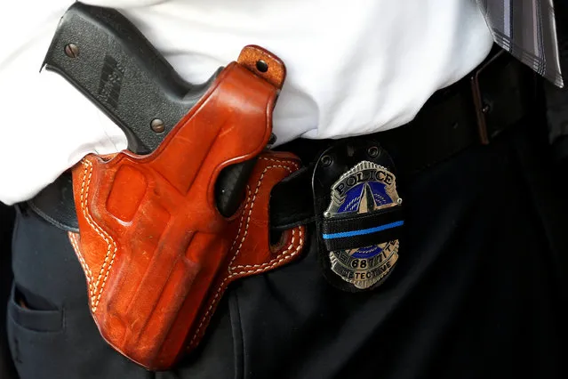 A Dallas police detective wears a mourning band on his badge kept next to his SIG Sauer gun during a candlelight vigil at Dallas City Hall following the multiple police shootings in Dallas, Texas, U.S., July 11, 2016. (Photo by Carlo Allegri/Reuters)