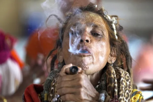 A Hindu holy woman smokes as she waits to register for an annual pilgrimage to the holy Amarnath cave, in Jammu, India, Monday, July 4, 2022. Thousands of Hindu devotees have begun the annual pilgrimage to an icy cave in Indian-controlled Kashmir amid massive security in the Muslim-majority region. (Photo by Channi Anand/AP Photo)