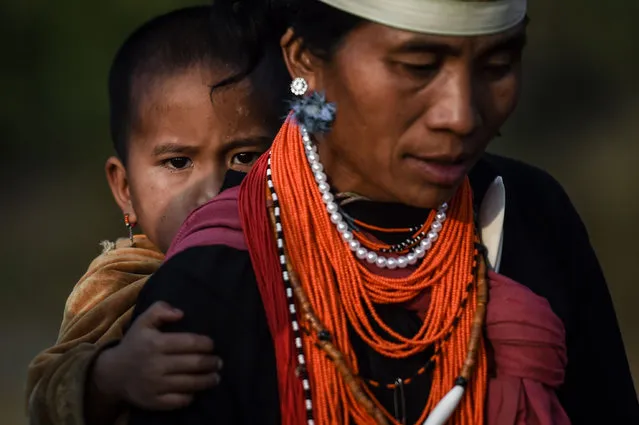 This photo taken on February 7, 2020 shows a Naga tribeswoman carrying a child at the end of an overnight ceremony to bless the harvest in Satpalaw Shaung village, Lahe township in Myanmar's Sagaing region. A haunting refrain pierces the night as the tribeswomen of the Gongwang Bonyo, among the most isolated people in Myanmar, dance around a campfire to bless the harvest ahead. (Photo by Ye Aung Thu/AFP Photo)