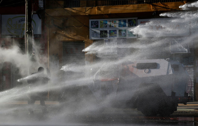 A demonstrator is hit by a jet of water from a riot police vehicle during a rally on the fourth anniversary of the protests and riots that rocked the country in 2019, Valparaiso Chile on October 18, 2023. (Photo by Rodrigo Garrido/Reuters)