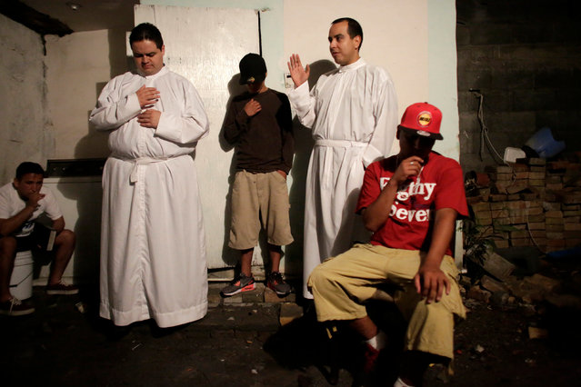 An aspiring Catholic priests Jose Luis Guerra (L) and Jose Luis Fernandez, members of Raza Nueva in Christ, a project of the archdiocese of Monterrey, bless young men during a visit to a neighbourhood in the municipality of Garcia, on the outskirts of Monterrey, Mexico, June 1, 2016. (Photo by Daniel Becerril/Reuters)