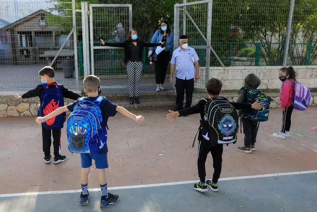 Israeli school principal Sigal Bar demonstrates to pupils wearing protective masks how to maintain social distancing, upon return to school after the COVID-19 lockdown, at Hashalom elementary in Mevaseret Zion, in the suburbs of Jerusalem, on May 3, 2020. Israeli elementary schools were given the green light to bring back students of first through third grades, as the country looks to gradually transition back into a more normal routine after seven weeks of confinement measures. (Photo by Emmanuel Dunand/AFP Photo)