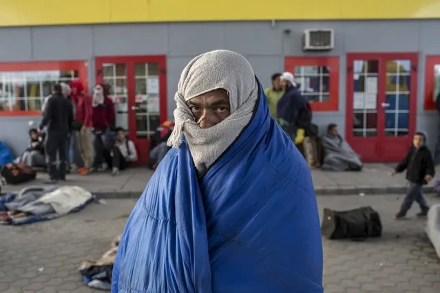 A migrant from Syria tries to warm himself at a gas station while waiting to be transported to a reception camp near the village of Roszke, Hungary September 6, 2015. (Photo by Marko Djurica/Reuters)