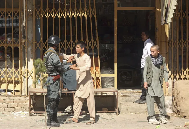 A policeman forbids a teenager to get closer to the site of a deadly suicide attack in Kabul, Afghanistan, Monday, July 24, 2017. A suicide car bomb killed over 20 people and injured many others early Monday morning in a western neighborhood of Afghanistan's capital where several prominent politicians reside. (Photo by Massoud Hossaini/AP Photos)