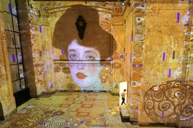 A person walks through an exit beneath an image of Adele Bloch-Bauer by artist Gustav Klimt during a press preview for Hall des Lumieres, a new permanent center for immersive digital art opening with the exhibition “Gustav Klimt: Gold in Motion” in Manhattan, New York City on September 13, 2022. (Photo by Andrew Kelly/Reuters)