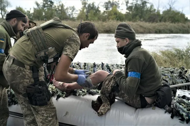 A Ukrainian serviceman is treated during an evacuation of injured soldiers participating in the counteroffensive, in a region near the retaken village of Shchurove, Ukraine, Sunday, September 25, 2022. (Photo by Leo Correa/AP Photo)