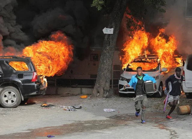 Men run with looted goods near cars on fire during protests over rising fuel prices and crime as inflation surged to its highest in a decade, in Port-au-Prince, Haiti on September 14, 2022. (Photo by Ralph Tedy Erol/Reuters)