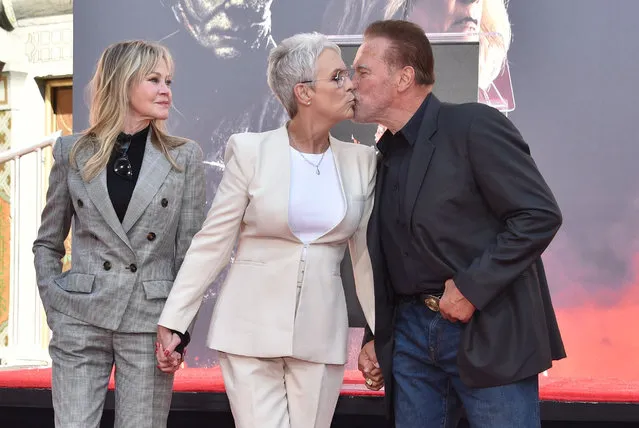(L-R) US actress Melanie Griffith looks on as US actress Jamie Lee Curtis give a kiss to Austrian-US actor and former Governor of California Arnold Schwarzenegger during her hand and footprint ceremony in the courtyard of the TCL Chinese theatre in Hollywood, California, on October 12, 2022. (Photo by Chris Delmas/AFP Photo)