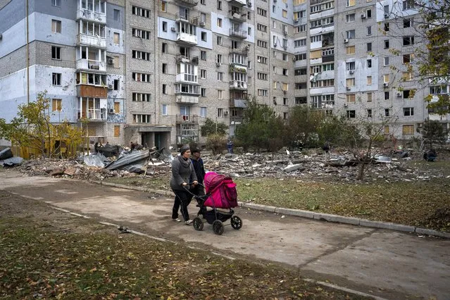 A couple pushing a baby stroller walks past a building damaged by a Russian missile in Mykolaiv, Sunday, October 23, 2022. (Photo by Emilio Morenatti/AP Photo)