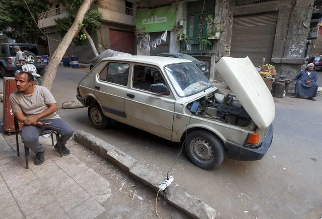 Ali al-Saeed, a 51-year-old Egyptian teacher, sits next to the charging cable of his 1985 Fiat-127 after turning the car into an electric one to save fuel amid rising prices, resorting to a more environmental-friendly mode of transportation, in Cairo, Egypt on October 12, 2022. (Photo by Amr Abdallah Dalsh/Reuters)