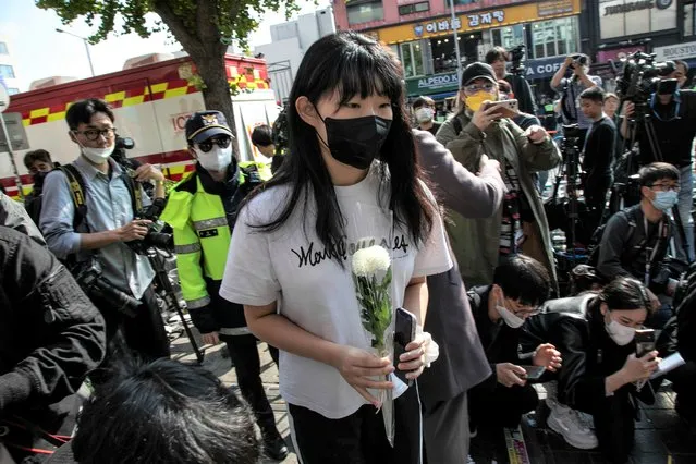 A young woman brings a flower to pay tribute at the accident site in Itaewon in Seoul, South Korea on October 30, 2022. (Photo by Jean Chung for The Washington Post)