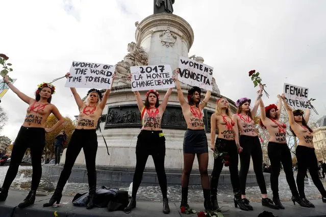 Activists from women's rights movement Femen, including leader Inna Shevchenko (4th R), stand topless while holding signs on the Place de la Republic in Paris on November 25, 2017 during a demonstration against violence against women. November 25 is the International Day for the Elimination of Violence Against Women. (Photo by Francois Guillot/AFP Photo)