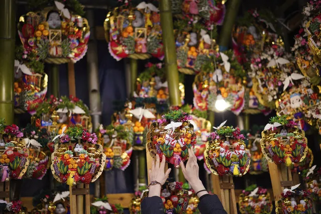 A worker displays various “Kumade” or “good luck rake” to sell during Torinoichi festival at a shrine in Tokyo Thursday, November 30, 2017. At the festival, many street stalls sell kumades decorated with lucky charms, shape of rakes that bring in prosperous business and good fortune. (Photo by Eugene Hoshiko/AP Photo)