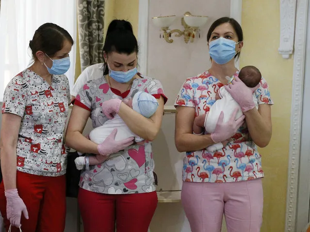 Nurses hold babies born from Ukrainian surrogate mothers prior to them meeting their parents, in Kyiv, Ukraine, Wednesday, June 10, 2020. Authorities in Ukraine have allowed foreign parents to enter the country and collect their babies, born to surrogate mothers and stranded in Ukraine after its borders shut down under coronavirus restrictions. Thirty-one couples have arrived to Ukraine and have reunited with the infants, while 88 more families were on the way, Ukraine’s human rights ombudswoman Lyudmila Denisova said Wednesday. (Photo by Efrem Lukatsky/AP Photo)