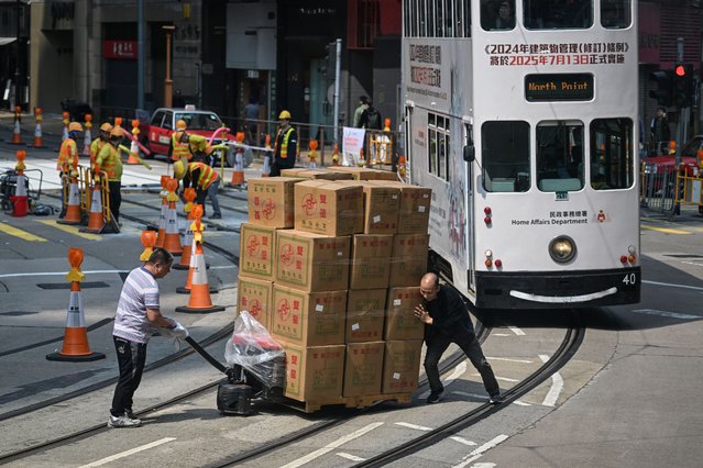 Two men push a pallet of goods over tram tracks in Hong Kong on April 2, 2025. Asian markets edged up as nervous investors brace for US President Donald Trump's wave of tariffs later in the day, though speculation about what he has in store is stoking uncertainty on trading floors. (Photo by Peter Parks/AFP Photo)