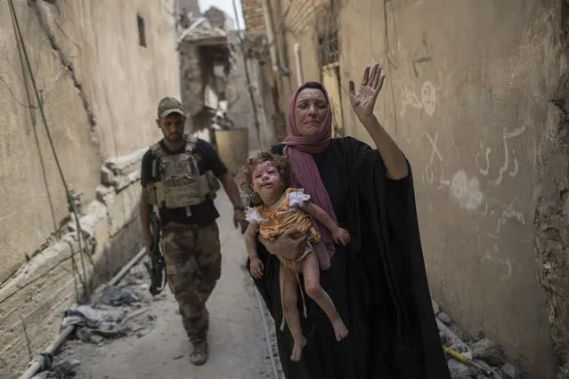 A woman holds a young injured girl as Iraqi forces continue their advance against Islamic State group militants in the old city of Mosul, Iraq, on July 3, 2017. (Photo by Felipe Dana/AP Photo)