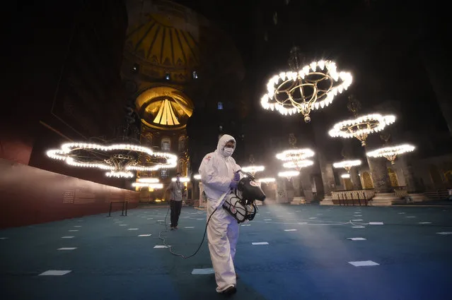 A few hours before prayers for the Islamic festival of Eid al-Adha, a municipality worker wearing protective clothing against the spread of coronavirus sprays disinfectant in the Byzantine-era Hagia Sophia, recently converted back to a mosque, in the historic Sultanahmet district of Istanbul, early Friday, July 31, 2020. This is the first Feast of Sacrifice since the onset of the coronavirus pandemic. The major Muslim holiday, at the end of the hajj pilgrimage to Mecca, is observed around the world by believers and commemorates prophet Abraham's pledge to sacrifice his son as an act of obedience to God. (Photo by Yasin Akgul/AP Photo)
