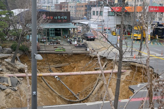 A general view shows a sinkhole on a road in Seoul on March 25, 2025. One person has been killed after a massive sinkhole opened up in Seoul, the fire department said, with harrowing video footage showing the moment his vehicle was swallowed by the hole. The vast hole opened up at an intersection in the southeast of the South Korean capital during the evening rush hour around 6:30 pm (0900 GMT) on March 24. (Photo by Anthony Wallace/AFP Photo)