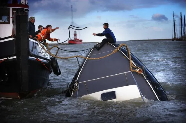 Rescuers try to save a sinking ship in the harbour of Harlingen in northern Netherlands, 22 October 2014, during the first autumn storm of the year. The remnants of Hurricane Gonzalo affected many parts of Europe. (Photo by Catrinus van der Veen/EPA)