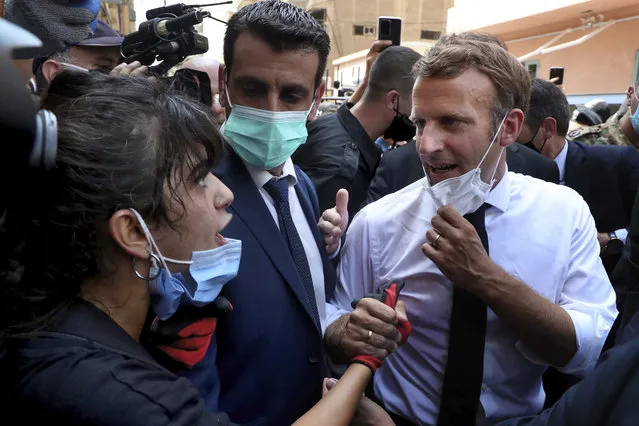 French President Emmanuel Macron, right, speaks with a woman as he visits the Gemayzeh neighborhood, which suffered extensive damage from an explosion on Tuesday that hit the seaport of Beirut, Lebanon, Thursday, August 6, 2020. Macron has arrived in Beirut to offer French support to Lebanon after the deadly port blast. (Photo by Bilal Hussein/AP Photo)