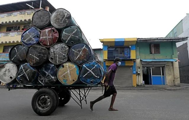 A man wearing a protective mask pulls a cart with metal barrels near a main market, amid concerns about the spread of the coronavirus disease (COVID-19), in Colombo, Sri Lanka, July 30, 2020. (Photo by Dinuka Liyanawatte/Reuters)