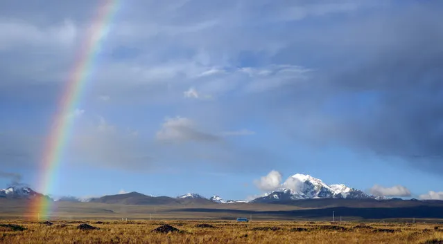 In this Saturday, April 25, 2015 photo, a rainbow is seen over a field with the Huayna Potosi mountain in the background as a bus drives by near Batallas, Bolivia. (Photo by Juan Karita/AP Photo)