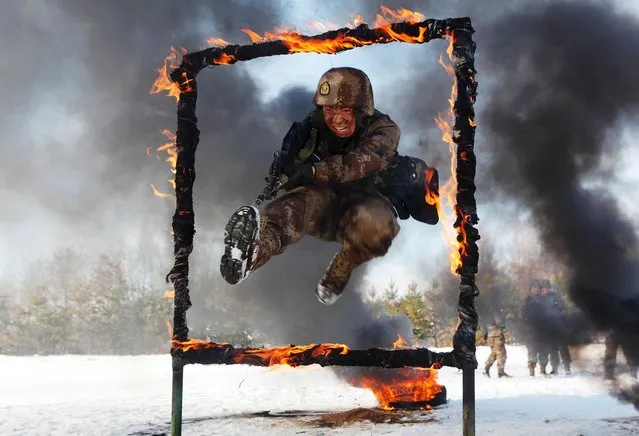 A People's Liberation Army soldier jumps over a burning obstacle during a training session on a snowfield, in Heihe, on November 2, 2014. (Photo by Reuters/Stringer)