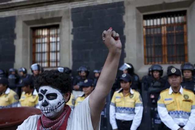A woman with her face painted to look like a skull raises her fist in front of traffic police as protesters (not pictured) belonging to the National Coordination of Education Workers (CNTE) teachers union take part in a march in Mexico City, Mexico, October 12, 2015. Thousands of teachers from the southern states marched against education reforms promoted by the government of President Enrique Pena Nieto, according to local media. (Photo by Jorge Dan Lopez/Reuters)