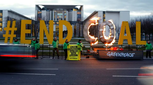 Greenpeace activists set a protest slogan reading “#end coal” on fire to protest against the opencast brown coal mining, in front of the office of German Chancellor Angela Merkel in Berlin, Germany, February 1, 2018. (Photo by Axel Schmidt/Reuters)