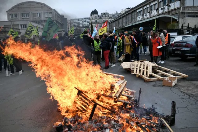 Wooden pallets burn, as demonstrators gather during a rally called by French trade unions in outside the Gare de Lyon, in Paris on January 19, 2023. A day of strikes and protests kicked off in France on January 19, 2023 set to disrupt transport and schooling across the country in a trial for the government as workers oppose a deeply unpopular pensions overhaul. (Photo by Stephane de Sakutin/AFP Photo)