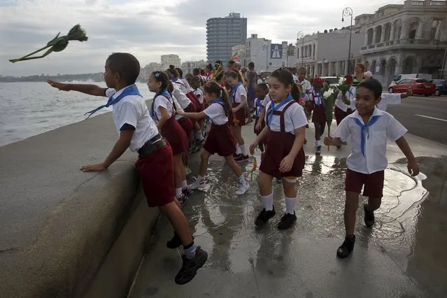 Schoolchildren throw flowers into the sea, in honor of rebel hero Camilo Cienfuegos, from Havana's seafront wall "El Malecon", October 28, 2015. (Photo by Reuters/Stringer)