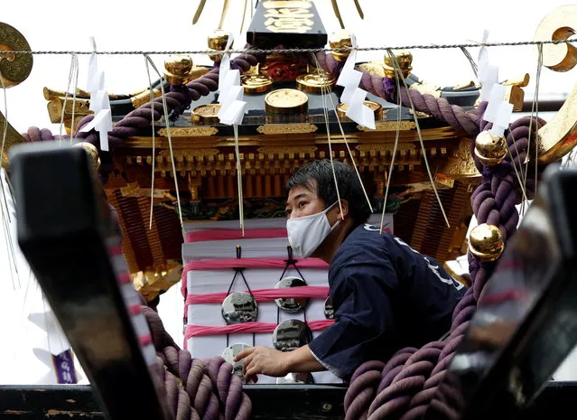 A reveller wearing a protective mask tries to load a Mikoshi or portable shrine onto a truck, while it's usually carried by the hands of revellers, under the infection control measures during Sanja Matsuri, one of the Tokyo's biggest traditional festivals, taking place after months of delay caused by the coronavirus disease (COVID-19) outbreak, at Asakusa district in Tokyo, Japan on October 18, 2020. (Photo by Issei Kato/Reuters)