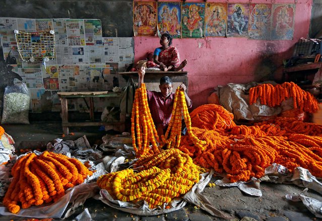 A vendor sells marigold garlands, which are used to decorate temples and homes during the Hindu festival of Durga Puja, at a wholesale flower market in Kolkata, India October 6, 2016. (Photo by Rupak De Chowdhuri/Reuters)