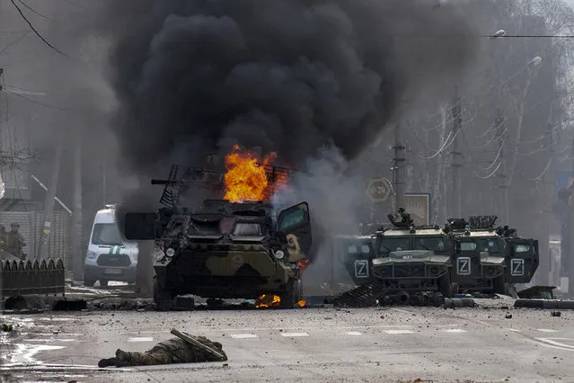 A Russian armored personnel carrier burns amid damaged and abandoned light utility vehicles after fighting in Kharkiv, Ukraine, Sunday, February 27, 2022. (Photo by Marienko Andrew/AP Photo)