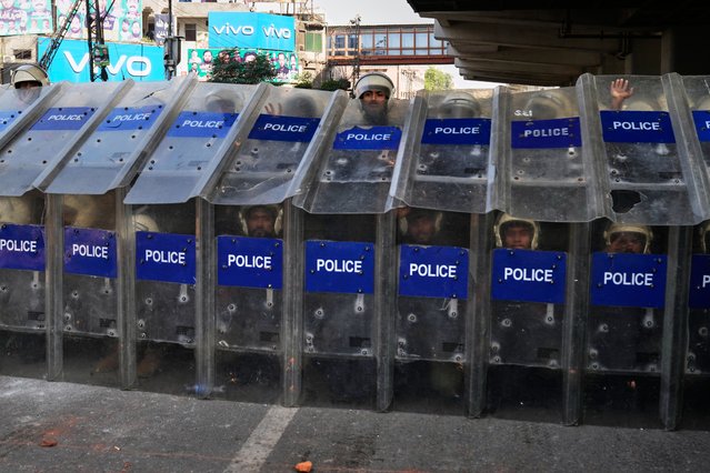 Police officers take positions behind shields close to the headquarters of Islamist party “Tehreek-e-Labbaik Pakistan” ahead of their pro-Palestinian march toward capital Islamabad, in Lahore, Pakistan, Thursday, October 9, 2025. (Photo by K.M. Chaudary/AP Photo)