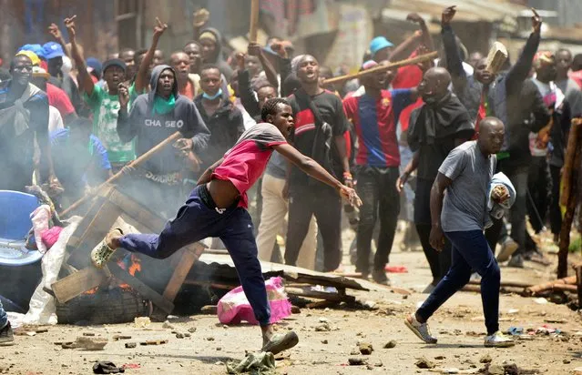 Supporters of Kenya's opposition leader Raila Odinga of the Azimio La Umoja (Declaration of Unity) One Kenya Alliance, throw stones at riot police officers as they participate in a nationwide protest over cost of living and President William Ruto's government in Mathare settlement of Nairobi, Kenya on March 27, 2023. (Photo by John Muchucha/Reuters)