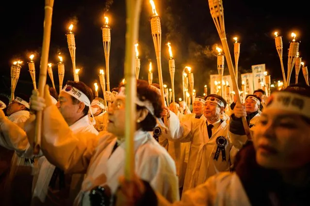 Participants wear traditional costumes as they hold fire torches, while marching to celebrate the March 1 Independence Movement anniversary in Cheonan, 90 kilometers south of Seoul on February 28, 2023. South Koreans celebrate the public holiday of remembrance to mark the 1919 civilian uprising against Japanese colonial rule from 1910-1945. (Photo by Anthony Wallace/AFP Photo)