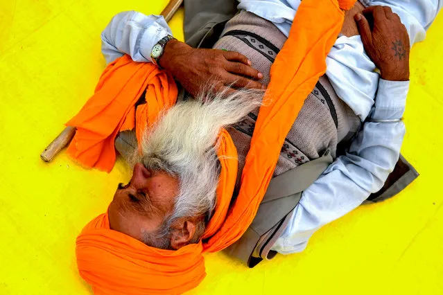 A farmer takes a nap along a blocked highway during a demonstration against the central government's recent agricultural reforms at the Delhi-Uttar Pradesh state border in Ghazipur on December 11, 2020. (Photo by Money Sharma/AFP Photo)