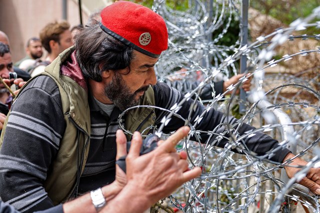Protesters try to remove the barbed wire fence forming the security perimeter outside the government palace headquarters in the centre of Beirut on March 22, 2023 during a demonstration by retired Lebanese army and security forces veterans demanding inflation-adjustments to their pensions. (Photo by Joseph Eid/AFP Photo)