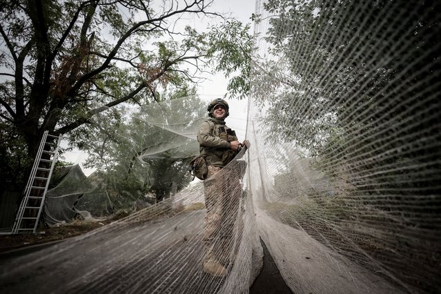 A member of the Ukrainian armed forces installs anti-drone nets over a road in the Donetsk region on October 14, 2025. (Photo by Ukrainian Armed Forces/Reuters)