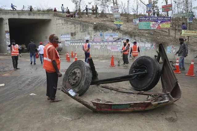 Volunteers stand near the wreckage of a bus that fell into a roadside ditch in Shibchar area in Madaripur district, Bangladesh, Sunday, March 19, 2023. More than a dozen people were killed and more were injured in the accident. (Photo by Jibon Ahmed/AP Photo)