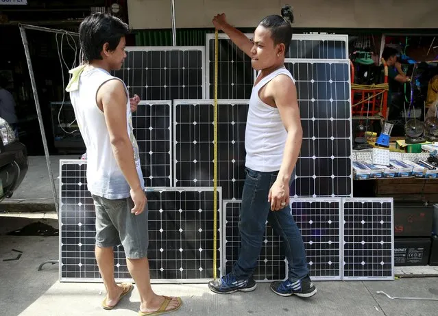 A vendor measures the length of a solar panel while a buyer looks on at a stall in Manila July 13, 2015. (Photo by Romeo Ranoco/Reuters)