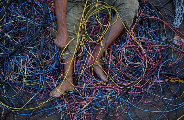 A man removes copper wiring from electrical cables outside a scrap shop in Dharavi, Mumbai, India December 10, 2012. (Photo by Danish Siddiqui/Reuters)