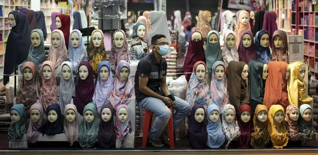 A shop vendor wearing a face mask to help curb the spread of the coronavirus waits for customers in downtown Kuala Lumpur, Malaysia, on Tuesday, November 3, 2020. Malaysia extended restricted movements in its biggest city Kuala Lumpur, neighboring Selangor state and the administrative capital of Putrajaya from Wednesday in an attempt to curb a sharp rise in coronavirus cases. (Photo by Vincent Thian/AP Photo)