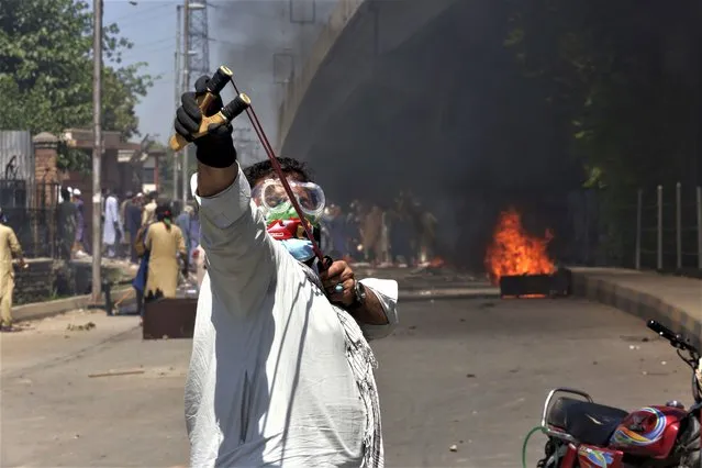 A supporter of Pakistan's former Prime Minister Imran Khan throws stones using a slingshot toward police officers during a protest against the arrest of their leader in Peshawar, Pakistan, Wednesday, May 10, 2023. Pakistan braced for more turmoil a day after Khan was dragged from court in Islamabad and his supporters clashed with police across the country. The 71-year-old opposition leader is expected in court later Wednesday for a hearing on keeping Khan in custody. (Photo by Muhammad Sajjad/AP Photo)